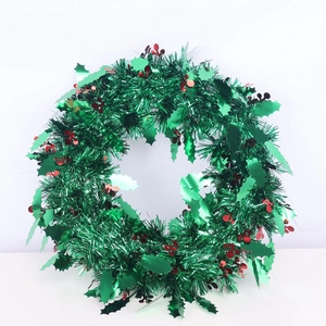 Detail of green sequin tinsel Christmas wreath with red ornaments on white background