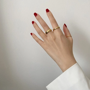 Three minimalist gold adjustable rings worn by a model with elegant red nail polish