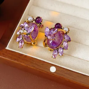 Vintage style gold earrings with purple zircon oval stones and pearls in a jewelry box