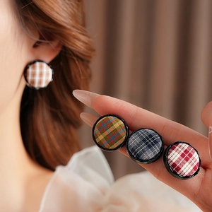 Close-up of stylish fabric button stud earrings with classic colorful plaid patterns