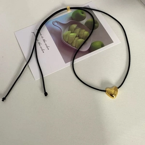 Minimalist black cord necklace featuring a polished gold heart pendant and adjustable bead