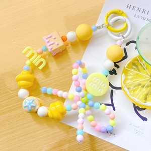 Detail of colorful beaded phone strap with star and flower charms on wooden table