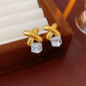 Macro shot of gold cross stud earrings with square crystal in a velvet jewelry box