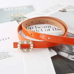 Orange skinny leather belt with pearl and rhinestone buckle on fashion magazines