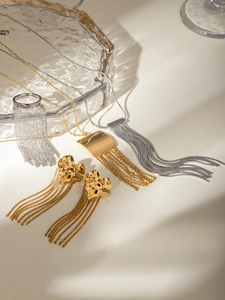 Close-up of gold and silver tassel earrings and necklace jewelry on glass texture