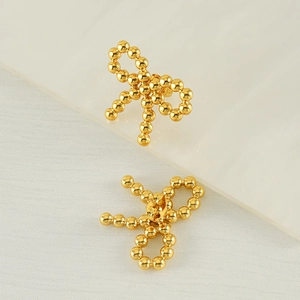 18k gold plated stainless steel bow earrings made of small metal beads on fabric background