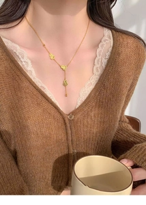 Detail of 18k gold-plated double gourd pendant necklace worn on a model in soft light