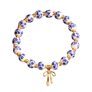 Bracciale in ceramica blu con dettagli dorati e ciondolo a fiocco con strass lucidi