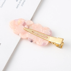 Detail of pink floral acetate hair clip with golden metal duckbill clasp and marble texture