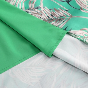 Detailed close-up of green botanical print fabric and quality stitching on the dress