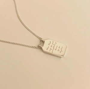 Macro detail of silver rectangular pendant necklace with engraved inspirational quote