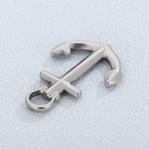 Polished stainless steel anchor pendant with cross detail on light textured background