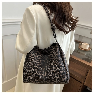 Leopard print tote bag detail showing knotted shoulder strap and leather texture on model