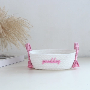 Detailed macro of white cotton rope basket with pink handles and 'goodday' embroidery