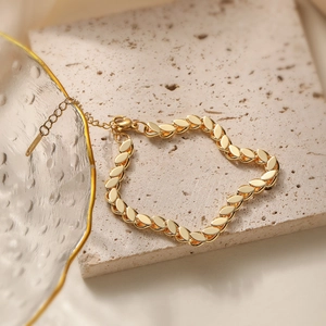 Elegant 18K gold-plated stainless steel leaf link bracelet displayed on a stone pedestal
