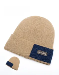 Detail view showing khaki knitted beanie with navy color-block and fashion leather label