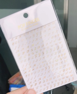 Detail of MG720 gold holographic 3D letter nail stickers in clear packaging with card