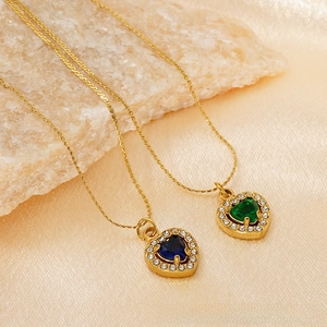 Macro detail of heart-shaped blue and green crystal pendants on gold snake chains