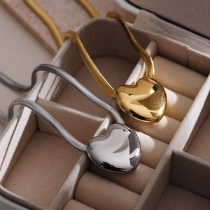Close-up of gold and silver heart-shaped pendants on thick snake chains in a jewelry box
