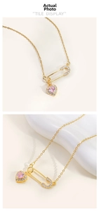 Macro detail of gold-plated safety pin necklace with pink heart-shaped gemstone pendant