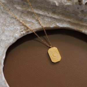 Gros plan d'un pendentif rectangulaire lune et météore plaqué or 18K sur cuir marron
