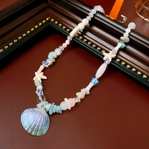 Macro detail of ocean-style necklace with pearl, seashell beads and starfish charm