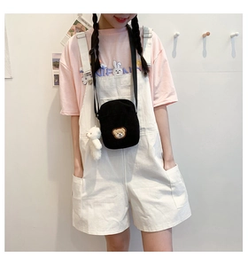 Close-up of black corduroy crossbody bag featuring a cute bear patch and plush charm