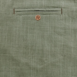 Detail of chest pocket on grass green cotton linen shirt with brown button and texture