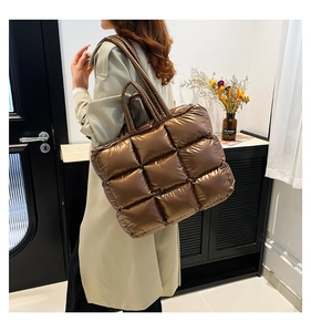 Vista dettagliata di una borsa tote trapuntata grande color marrone metallizzato sulla spalla