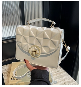 Close-up of cream quilted PU leather bag with elegant golden circular metal buckle