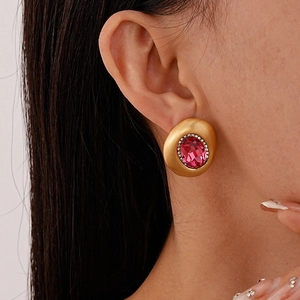 Nahaufnahme von Vintage-Ohrsteckern in Gold mit ovalem rosa Stein und Glitzerrahmen