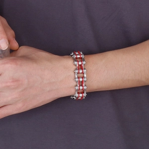 Detailed close-up of heavy industrial silver chain bracelet with red mechanical accents