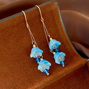 Vue macro de boucles d'oreilles fleurs en résine bleue avec crochets dorés
