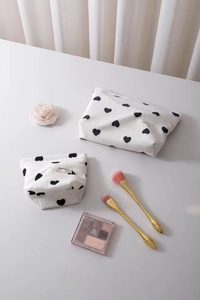 Close-up of waffle texture makeup bags with black heart prints and H&R BAG label