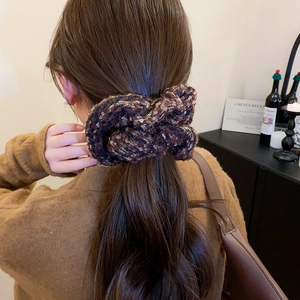 Détail d'un chouchou en tweed tricoté avec paillettes porté sur une queue de cheval