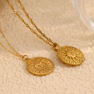 Détail de colliers avec pendentifs soleil et croissant de lune dorés style vintage