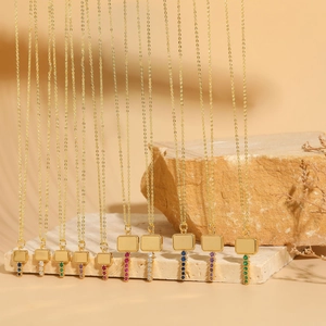 Detailed close-up of gold cross chain necklaces with colorful zircon stones on stone blocks