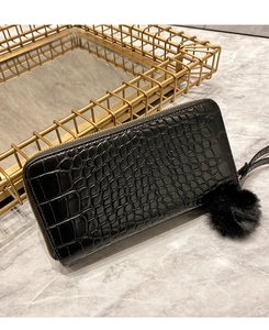 Close-up of black crocodile pattern long wallet with zipper and fluffy pompom keychain