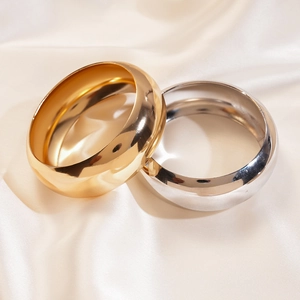 Detail of wide metallic gold and silver bangles on elegant beige silk fabric
