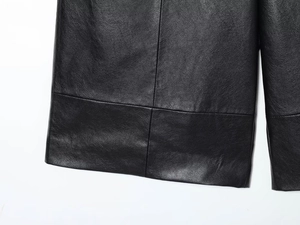 Detailed macro view showing cross-stitch seams and texture on black faux leather shorts