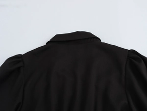 Detail view of the pleated back neck and puff sleeve shoulder on a black French dress