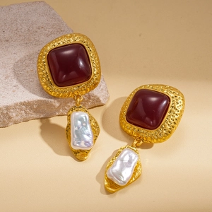 Detail of vintage gold earrings featuring square red resin gems and baroque pearls