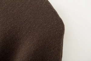 Makroaufnahme der dunkelbraunen Poncho-Stricktextur mit weichen, hochwertigen Faserdetails