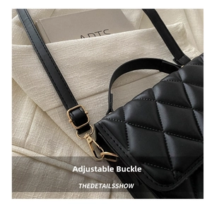 Détail de la bandoulière réglable avec boucle en métal doré sur sac matelassé noir
