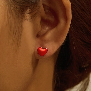 Close-up of S925 silver stud earring with a red heart design worn on an earlobe