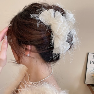 Gros plan sur la pince à cheveux en acrylique à plumes blanches et dentelle