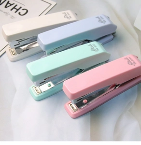 Pastel Morandi staplers in cream, blue, mint, and pink on a soft fabric background