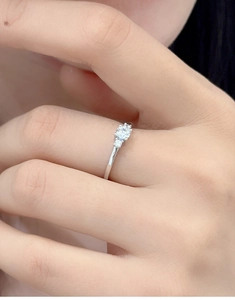 Close-up of S925 silver ring featuring three sparkling moissanite stones on a finger