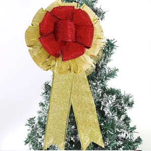 Macro shot of a red and gold glitter Christmas bow ornament on a snowy pine branch