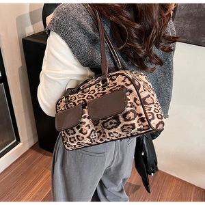 Detail view of leopard print shoulder bag with brown trim and front magnetic pockets